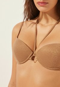 En tanfarvet strapless bikini top med polstrede skåle, der har en glitrende tekstur og et guld-ring akcent i midten.