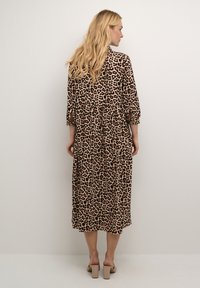 Rochie midi cu imprimeu de leopard, cu mâneci lungi, strânse și talie cinzută. Material moale cu o textură fluidă. Purtați cu sandale cu toc bloc.