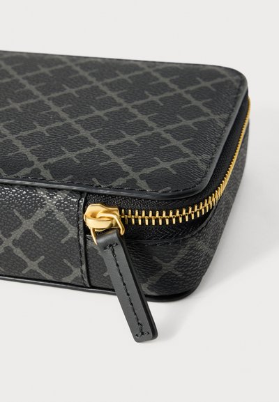 Μαύρο τσαντάκι φερμουάρ με υφή και γεωμετρικό σχέδιο, χρυσό μεταλλικό φερμουάρ και μαύρη δερμάτινη λεπτομέρεια στο σύρτη του φερμουάρ.