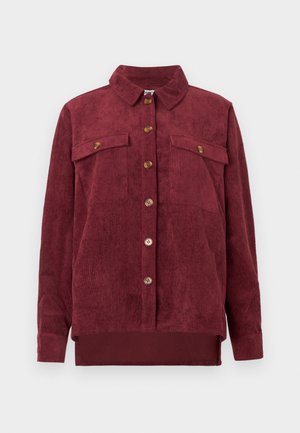 Camisa jaqueta de côr burgundy em corduroy com colarinho, botões frontais e dois bolsos no peito, apresentando uma textura em nervuras verticais e uma bainha reta.