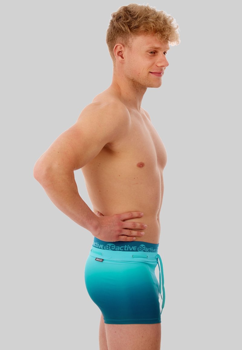 Aqua gradient men's swim trunks with a drawstring waist and logo waistband. Smooth, stretchy material, fitted design, mid-thigh length.