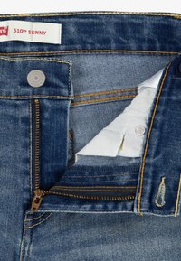 Jeans Levi's 510 Skinny, de mezclilla azul oscuro, con cremallera, herrajes de latón, costuras doradas, forro interior blanco, etiqueta que muestra el nombre del producto.