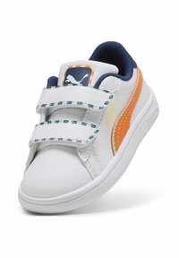 Baskets synthétiques blanches avec des accents orange et des détails bleus, comportant deux bandes velcro et une semelle texturée pour une meilleure adhérence.