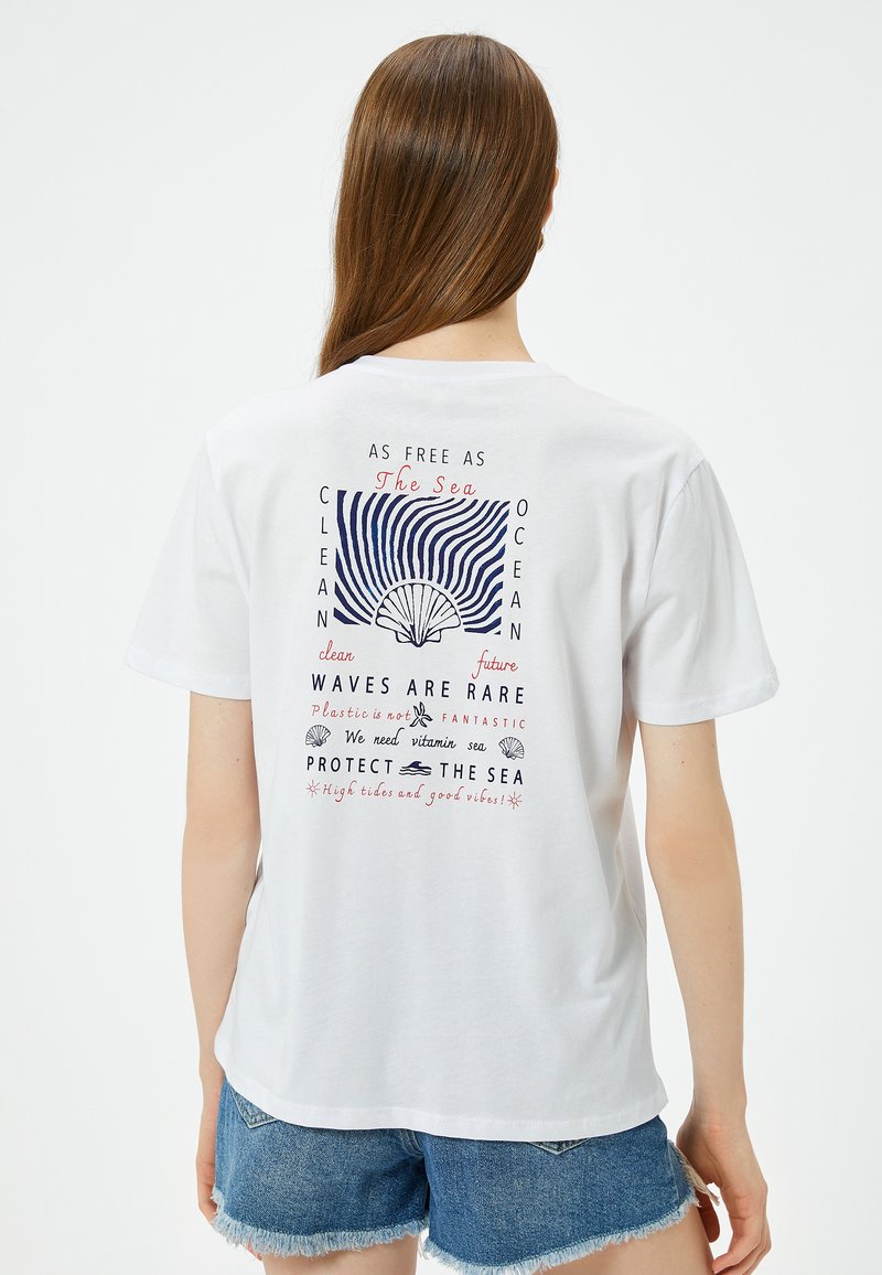 Hvid bomulds T-shirt med et farverigt grafik på ryggen med havrelateret tekst og et skalkoncept, kortærmet og med en afslappet pasform.