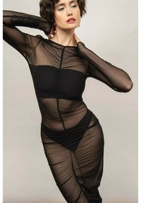 Czarna przezroczysta sukienka z długimi rękawami, marszczonym materiałem, zapinana z przodu na suwak i dopasowaną sylwetką na czarnym dopasowanym bieliźnie.