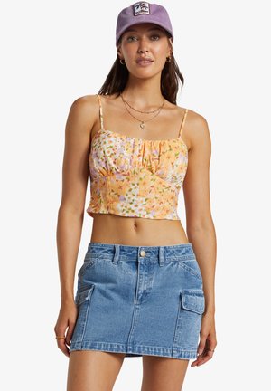 Crop top in orange with floral patterns, paired with a light blue denim mini skirt featuring front pockets. Lavender cap completes the look.
