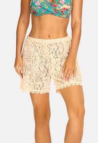 Szorty koronkowe w jasnym brzoskwiniowym kolorze z kwiatowym wzorem. Posiadają falbaniasty dół i elastyczną talię. Lekki, oddychający materiał.