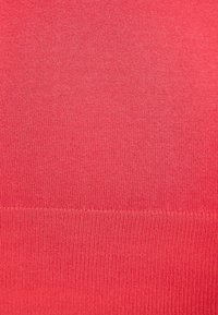 Tejido de punto en un color coral sólido, con una textura suave y un sutil relieve. Superficie uniforme y sin diseños o patrones visibles.