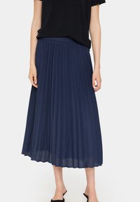 Marinblå veckad midikjol med elastisk midja, tillverkad av lätt material, med mjuk textur och flödande design.