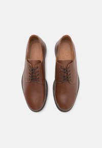 Scarpe in pelle marrone con finitura liscia, design con lacci, punta arrotondata e soletta testurizzata. Suola in gomma nera con bordi rialzati.