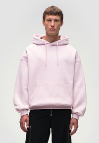 Jasnoróżowa bluza z kapturem wykonana z miękkiego materiału, z kangurzą kieszenią, regulowanymi sznurkami i dyskretnym logo na klatce piersiowej.