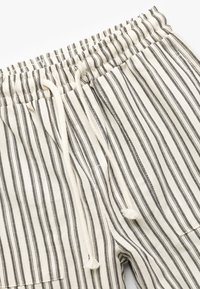 Gestreifte Hose aus leichtem Stoff; verfügt über einen Kordelzugbund und seitliche Taschen mit einem Muster aus dünnen schwarzen und cremefarbenen Streifen.