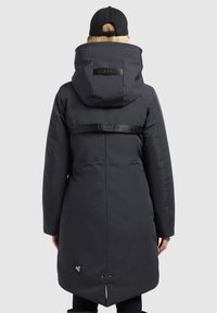 Long black puffer jacket with a high collar, adjustable hood, and a glossy brand strap across the back. Features a vent at the hem.