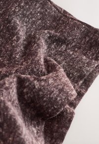 Texturált, sötét bordó szövet, amely puha, bolyhos felülettel van behintve, finom árnyalatokkal és meleg, barátságos megjelenéssel.