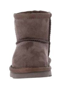 Stivale alla caviglia in suede marrone con una consistenza morbida, forma arrotondata, dettagli cuciti e una suola in gomma bassa. Design chiuso con un semplice sopra.