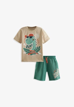T-shirt in cotone beige con grafica di un dinosauro, pantaloni corti verdi con cordino e accenti bianchi, che recano il testo "RAWR".