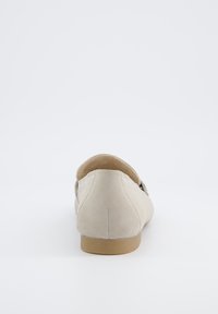 Mocassini in suede beige con punta rotonda, suola piatta e dettagli di cucitura minimi. Il design presenta una finitura testurizzata e sottile.