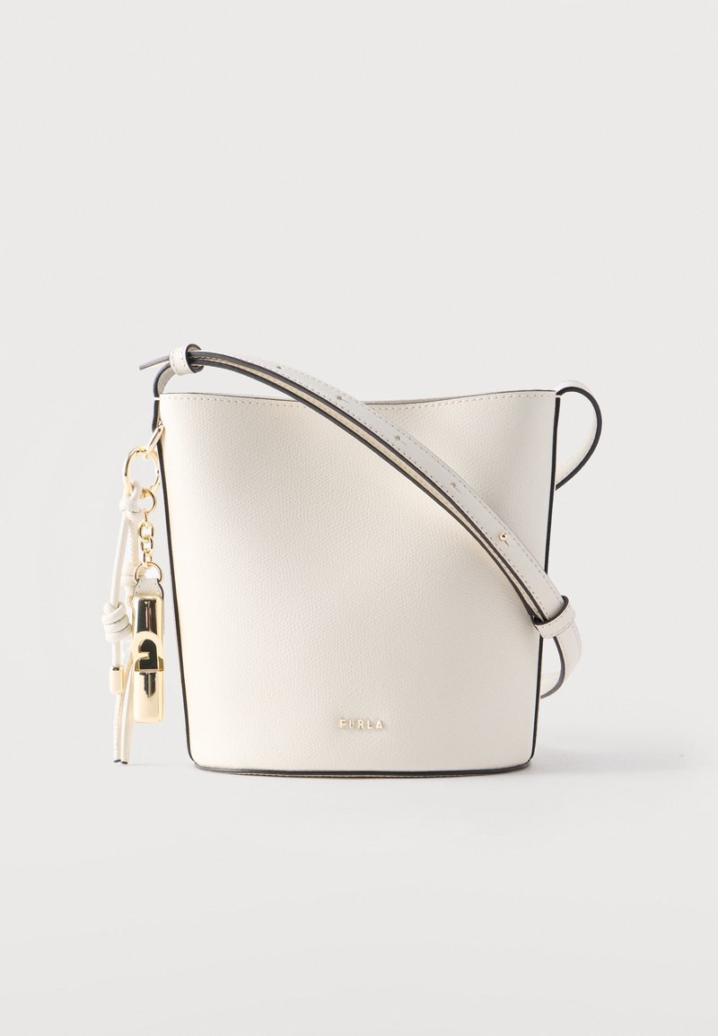 Λευκή τσάντα χειρός Furla τύπου κουβά με ρυθμιζόμενο λουρί ώμου και χρυσό κλείδωμα ως διακοσμητικό στο πλάι πάνω σε απλό φόντο.