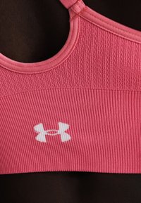Ροζ ριμπ αθλητικό σουτιέν με το λογότυπο Under Armour τοποθετημένο στο κέντρο κάτω από το ντεκολτέ.