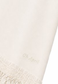 Tissu couleur crème avec une délicate bordure en dentelle et "Oh April" brodé près du bord avec un fil assorti.