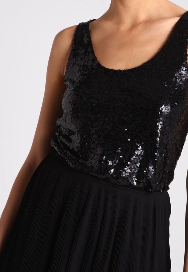 Robe noire avec un corsage en sequins et une jupe plissée. Le corsage est ajusté, tandis que la jupe flotte librement. Texture de tissu lisse.