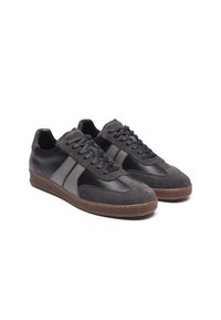 Svarte og grå sneakers har en kombinasjon av lær og semsket skinn, en gummisåle, flate snørebånd, og to side-striper i grått.