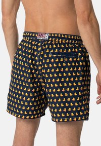 Pantaloni da bagno con uno sfondo blu navy e piccoli motivi ripetuti di paperelle di gomma gialle; vita elasticizzata con dettaglio della tasca sul retro.