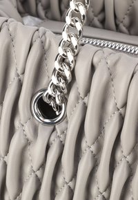 Borsa in pelle grigia con un design trapuntato testurizzato, dotata di una tracolla in catena argentata e un occhiello metallico, che mette in risalto i suoi accenti hardware moderni.