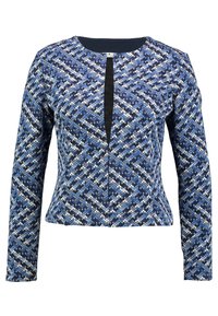 Niebieska bluzka z długim rękawem w wzór diamentu z teksturą, z czarnym akcentem pośrodku i okrągłym dekoltem.