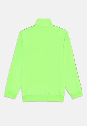 Neonzelena pulover jakna s visokim okovratnikom, dugim rukavima i rebrastim manžetnama. Glatka tekstura i kontrastne crne bočne pruge.