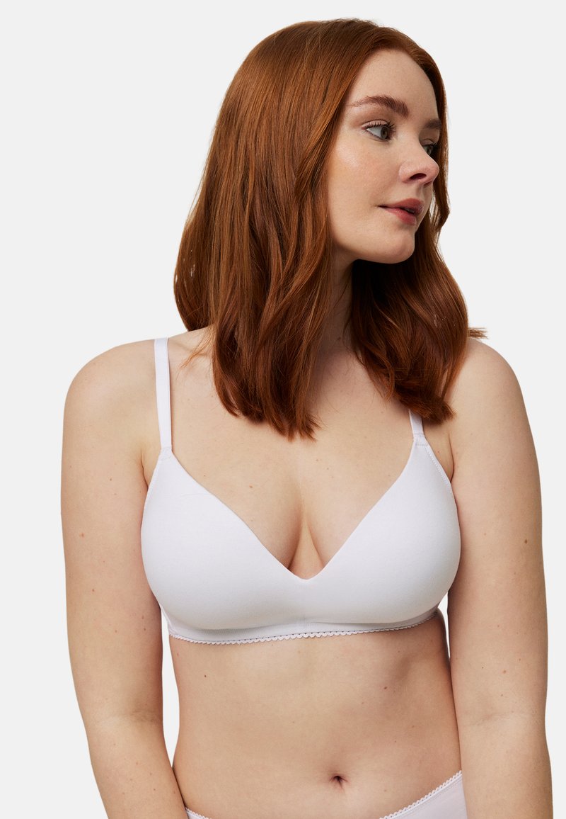 Sujetador inalámbrico blanco con escote pronunciado, tirantes delgados ajustables y borde festoneado a lo largo de los bordes. Textura de tela suave.