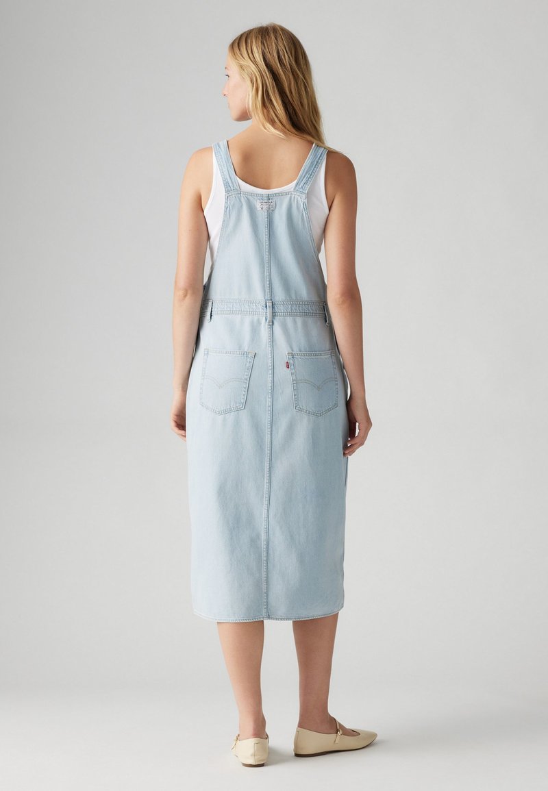 Helles blaues Jeans-Midikleid mit verstellbaren Trägern und geradem Schnitt, ausgestattet mit Vorder- und Gesäßtaschen und einem gesäumten Saum.