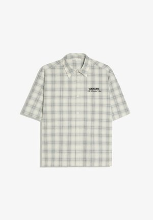 Chemise à manches courtes avec boutons, motif à carreaux blanc et gris et texte noir "VOIDCORE The Essential Ride" sur la poitrine gauche.