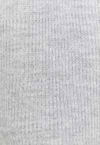 Zbliżenie na jasnoszary dzianinowy materiał o pionowej prążkowanej fakturze, z widocznymi miękkimi włóknami przędzy.