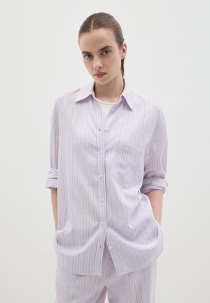 Camicia leggera a righe rosa e bianche con frontale a bottoni, maniche ripiegate e una tasca sul petto. Tessuto liscio.