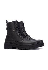 Botines negros con cordones, hechos de cuero sintético texturizado. Cuentan con una suela de goma gruesa y una lengüeta en la parte posterior para facilitar el calzado.