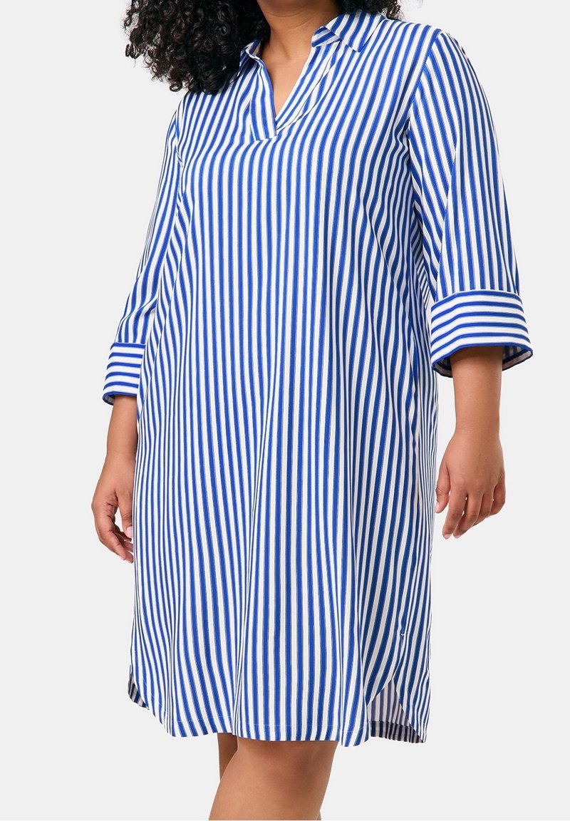 Robe rayée avec des rayures verticales bleues et blanches, col à revers, manches trois-quarts et fentes latérales à l'ourlet. Fabriquée en tissu léger.