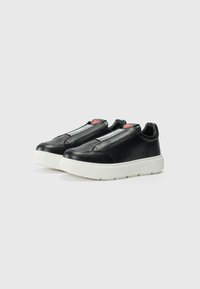 Zwarte leren sneakers met een witte rubberen zool, voorzien van een ritsdetail, geperforeerde accenten en een klein rood hart op de tong.