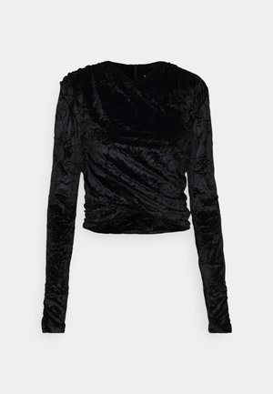 Svart långärmad topp i krinklad sammet, med en omslagsdesign och en figurnära silhuett med en mjuk textur.