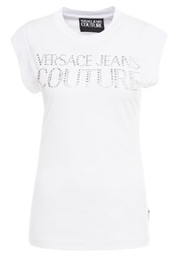 Bílá bavlněná T-shirt s krátkým rukávem, s nápisem "VERSACE JEANS COUTURE" ve stříbrných kamínkách na přední straně.