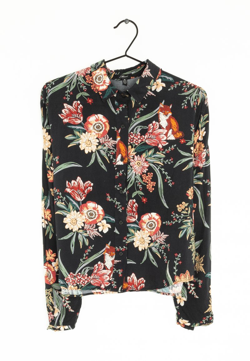 Chemisier noir à boutons, à manches longues, avec un motif floral et des illustrations de renards orange, suspendu sur un cintre noir contre un fond blanc.