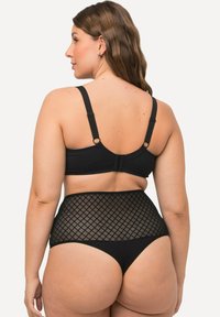 Zwarte bralette met verstelbare bandjes en een haaksluiting. Hoge zwarte slip met een diamanten gaaspaneel aan de tailleband.