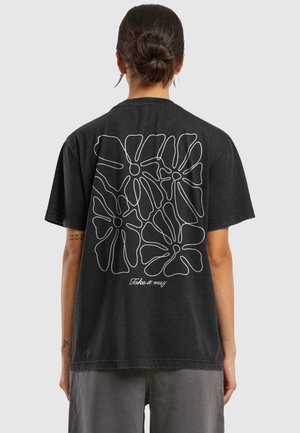 Black cotton t-shirt featuring a large white line art floral design on the back and the text "Take it easy" in cursive. Short sleeves.