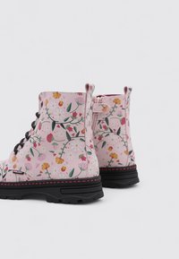 Botas de tobillo rosas con suelas negras y un estampado floral multicolor, que presentan cordones y una cremallera lateral para el cierre.