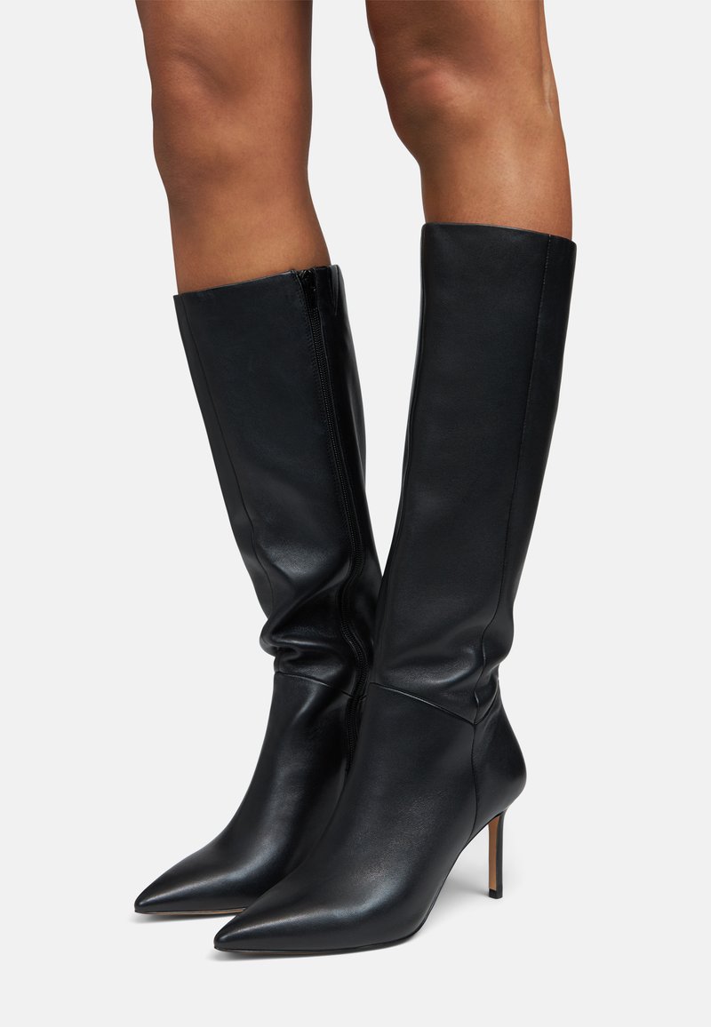 Juodi odiniai aukštakulniai batai iki kelių su smailiu nosimi ir plonu stiletto kulnu; turi šoninį užtrauktuką ir struktūrizuotą, elegantišką dizainą.