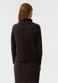 Maglione a costine di colore marrone scuro con collo alto e maniche lunghe; tessuto liscio, design aderente e lunghezza corta in uno stile semplice.