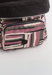Texturiertasche mit schwarzem Oberteil und einem Hauptkörper, der ein abstraktes Streifenmuster in Pink, Creme und Grün aufweist. Enthält eine vordere Reißverschlusstasche.