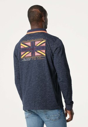 Navy langmouw poloshirt met een gestructureerde afwerking, voorzien van een kleurrijke Union Jack-afbeelding op de achterkant en een contrasterende kraagafwerking.