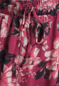 Tejido con patrón floral en tonos de rosa y negro, que incluye una cintura elástica con cordón ajustable. Textura suave y ligera.
