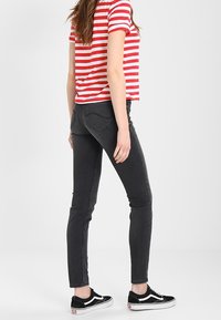 Röd och vit randig kortärmad t-shirt, svarta skinny jeans och svarta Vans sneakers. Jeansen har en klassisk 5-fickorsdesign.